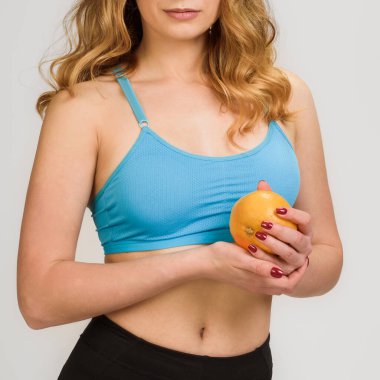 Meyve diyeti yapan zayıf, sağlıklı sporcu kadın elinde portakal tutuyor.