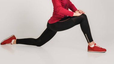 Genç esnek kadın bacakları gri arka planda aşırı bölünme yapıyor.