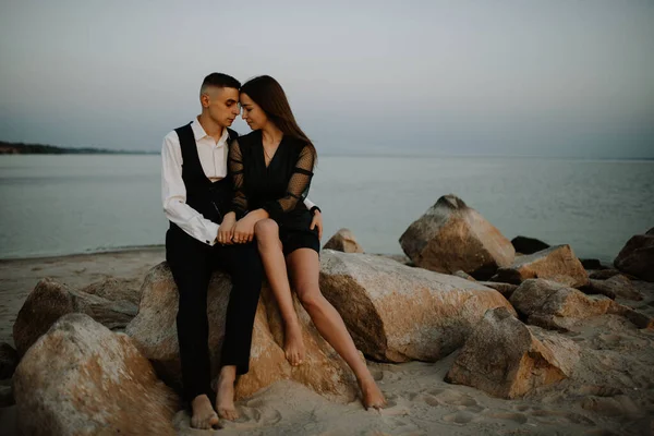 Gün batımında deniz kenarında el ele tutuşan sevgi dolu bir çift.