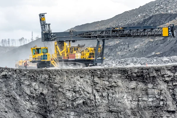 The drilling machine moves along the surface of the quarry ledge.