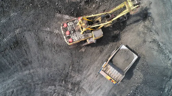 Cable excavator loads overburden from the body of a mining truck.