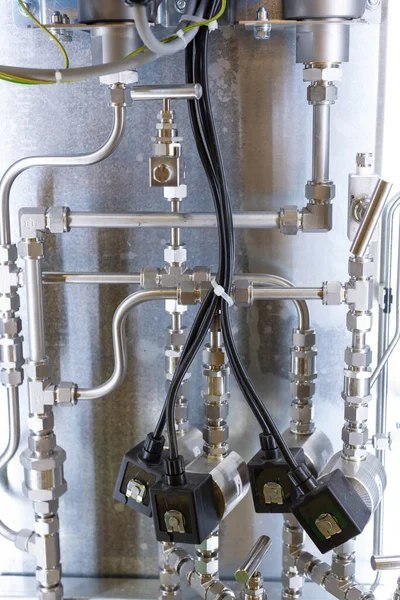 Piping of a chemical reactor. Many stainless steel tubes. Connection by tees, flanges and nuts.