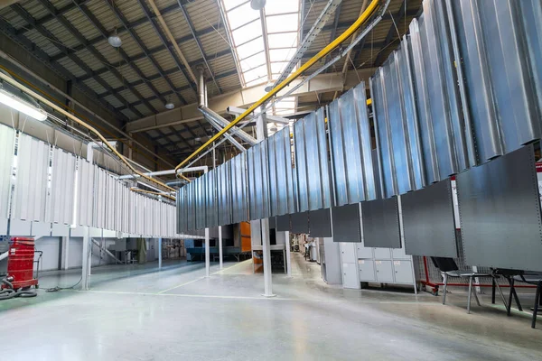 Powder coating line. Metal panels are suspended on an overhead conveyor line.