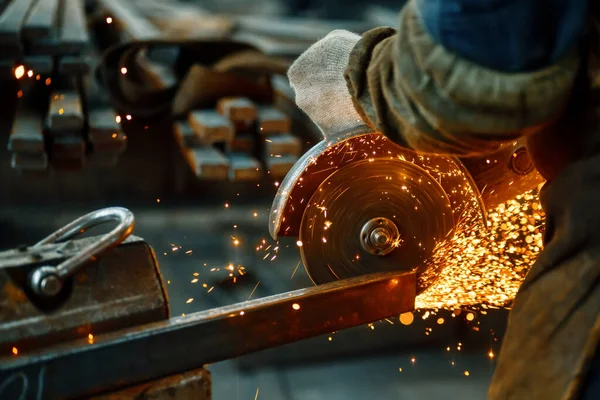 Cutting a metal beam using an angle grinder. A lot of sparks fly out from under the disk