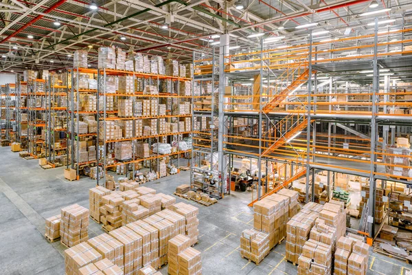 Large industrial warehouse. Tall racks are completely filled with boxes and containers.