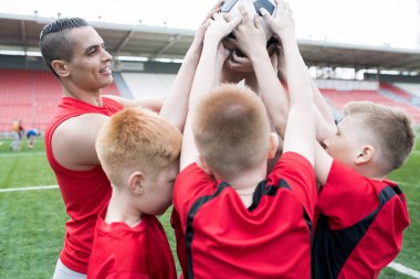 Topu bir arada tutan ve mutlu bir şekilde açık stadyum içinde kazanan maç sonra tezahürat genç futbol takımı portresi