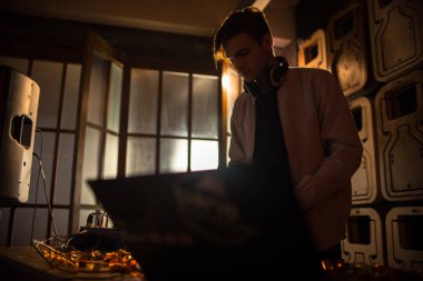 Trendy genç Dj Mikser kullanarak ve dizüstü ekran gece kulübü parti, kopya alanı bakarak müzik portresi