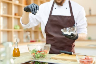 Bölüm yeşil salata ile modern restoran mutfak eldivenli ellerinde tuzlama modern profesyonel Chef, uzay kopya