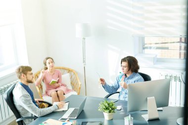 Renkleri gösterilen ve personel toplantısı sırasında onun seçimi sırasında raporlama yaratıcı yönetmen açıklayan gözlük ciddi kendine güvenen genç tasarım uzmanı