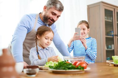 Küçük kız ise başka bir kızı alarak fotoğraf aile sahnesi mutfakta yemek öğretim gülümseyen baba portresi