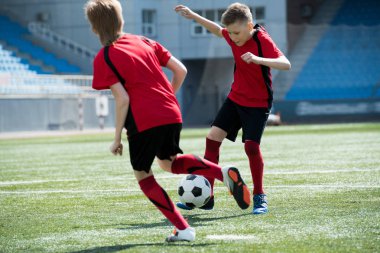Full length portrait of two teenage boys playing  football in stadium during junior team practice, copy space clipart
