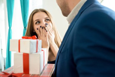 Karısı, Genç kadın koca sürpriz heyecandan ağzına kapsayan için hediyeler yığını tutan takım elbiseli adam Close-up