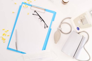 Görünüm flatlay Doktor araçları beyaz masa üzerinde yukarıda. Kompozisyon Pano, gözlük ve tansiyon, kopya alanı