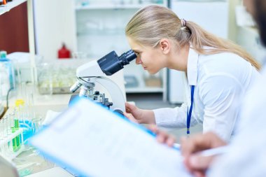 Konsantre genç kadın biyolog örnek modern laboratuvar analiz edilirken mikroskop arıyor