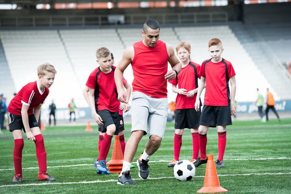 Uzunluk portre genç futbol takımı'nın pratik tam, kas koç önde gelen topu ön planda, kopya alanı odaklanmak