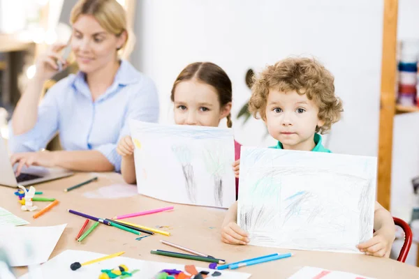 Portrait Deux Mignons Enfants Assis Table Montrant Leurs Propres Photos — Photo