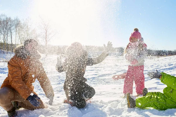 父母和他们的孩子在美丽的冬天下午在乡下投掷雪和享受乐趣 — 图库照片