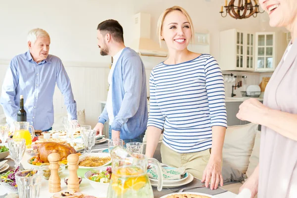 Portrait of happy two generation family preparing dinner together serving table with delicious homemade dishes for holiday party  in modern sunlit apartment