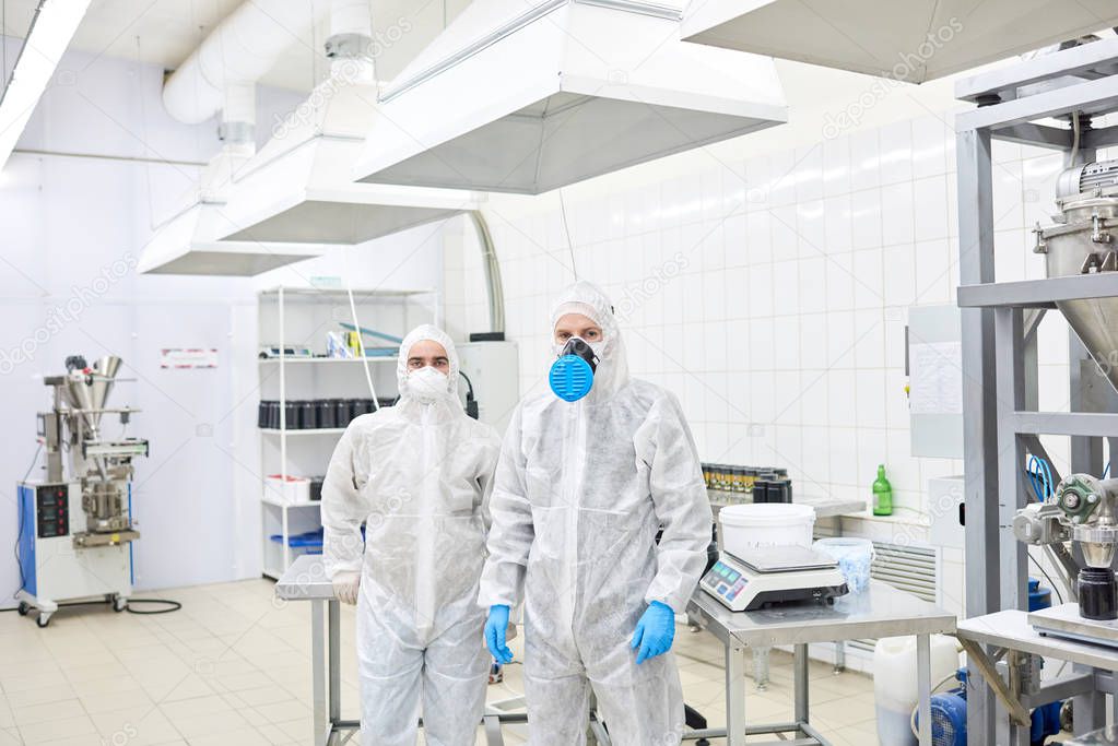 Two sports nutrition production workers standing in protective clothing and looking at camera.