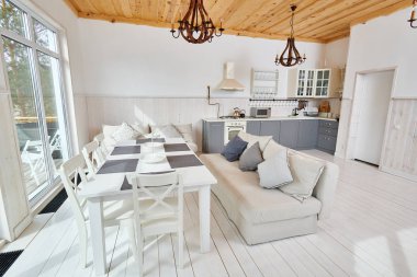 Geniş açı çekim Beyaz ahşap masa ve gri mutfak tezgahları güneş ışığı tarafından kopya alanı, yaktı minimalist İskandinav tasarım modern açık oturma odası kimse