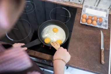 Anonim genç adam mutfakta ayakta ve yalnız zaman harcama yaparken kahvaltıda yumurta hazırlanıyor. 