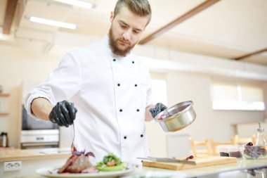 Yakışıklı profesyonel şef servis et tabağı modern restoran mutfakta yemek yaparken portresi