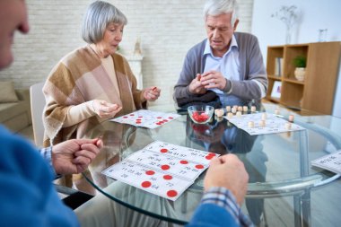 Yardımlı yaşam ev masada oturma odasında toplama ve Loto masada oynarken üst düzey hastalar. 