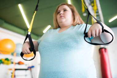 Kilolu kadın ile modern bir spor salonu makinelerde egzersizleri yapıyor düşük açılı portresi
