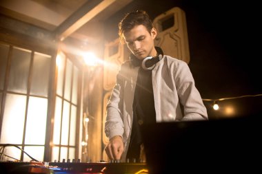 Trendy genç Dj Mikser kullanarak müzik portresi açı düşük ve gece kulübü parti dizüstü ekran baktığımızda, kopyalama alanı