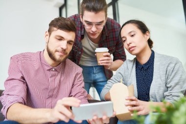 Öğle yemeği sırasında Smartphone cep telefonu ile video izlemek zorla Genç beyaz ofis çalışanları bölge sakin ol.