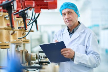 Burada boru ve vanadan modern atölye holding clipboard, kopya alanı içinde üretim kalite kontrol beklemede yapıyor üst düzey fabrika işçisi portresi kadar bel