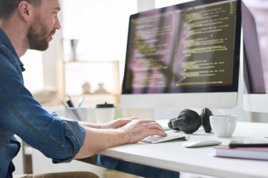 Ciddi dalgın deneyimli erkek programcı modern konforlu ofis yeni yazılım uygulaması çalışırken bilgisayarda kod yazarak
