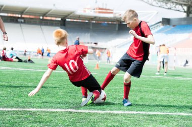 Tam uzunlukta portre üzerinde çim futbol sahası üzerinde topu genç takım antrenman sırasında savunmak başka bir oyuncu tarafından ele sonra düşen genç çocuk