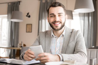 Neşeli başarılı yakışıklı genç işadamı süre restoranda takvim planlama ve neşeyle kameraya gülümseyen smarphone kullanarak şık ceketli
