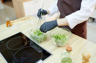 Tanınmayan kadın şef pişirme salata duran lokanta mutfağı, tahta masada kopya alanı