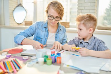 Babalar günü, iç arka plan üzerinde modern sınıf için yaratıcı hediye yaparken doğru makas kullanmak nasıl şirin küçük öğrenci öğretim gündelik giysiler içindeki genç ve güzel özel öğretmen