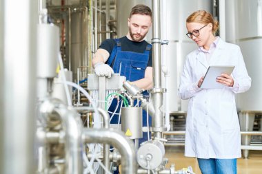 Yakışıklı sakallı teknisyen tulum giyen kadın üstün tutma gözü onun üzerinde ise modern ekipman ayarlama sarılmış