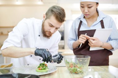 Modern Restoran mutfağında, kopya alanı pişirme sırasında güzel vegan yemek hizmet veren yakışıklı profesyonel şef portresi