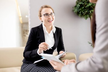 Formal giyim toplantı salonu ile elinde not etmek ve yaratıcı fikirler meslektaşı ile paylaşımı rahat kanepe üzerinde oturan genç ve güzel Manager'da portresi