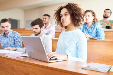 Üniversitesi masa başında oturan ve öğretim görevlisi, Afrikalı-Amerikalı kızla ciddi Afro saç modeli dizüstü bilgisayarda yazarak dikkatle dinlemeye dalgın konsantre genç çok ırklı öğrenciler