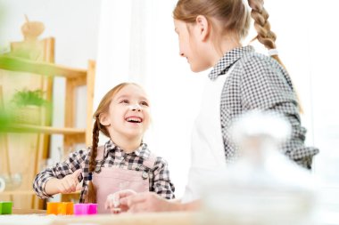 Portre sevimli küçük kız gülerek odaklanmak eğleniyor birlikte mutfakta yemek yaparken iki oynak kız kardeşlerin kurabiye, yapma