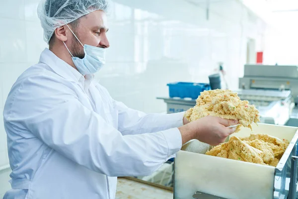 新鮮な生地を機械に入れて白衣の菓子工場労働者の側面図 — ストック写真