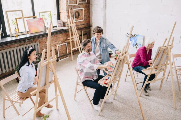 コピー スペース とした日当たりの良いアート スタジオ イーゼルの絵画の学生のグループでの作業の女性美術教師の広角の肖像画 — ストック写真