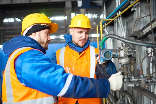 近代的な工場と調整装置の広々 とした製造部門に制服と Hardhats を身に着けているひげを生やした技術者のグループが集まった — ストック写真