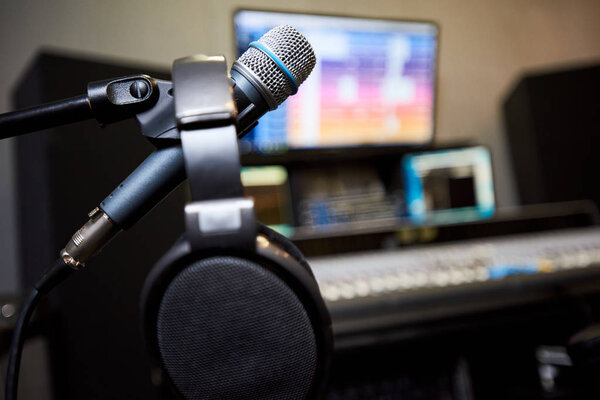 Close-up of microphone and earphones inside of sound studio working space for music recording. 