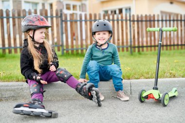 Giyen iki sevimli çocuk portresi tam uzunlukta frenlemek oturan dişli sürme ve mutlu bir şekilde gülümseyerek kameraya, kopyalama alanı