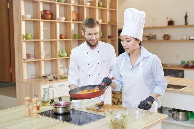 Asyalı kadın şef pişirme sebze kızartma tavası holding portresi modern restoran mutfak, kopya alanı ocağı