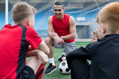 Portre yakışıklı genç Teknik Direktörü-gülümseyerek mutlu bir şekilde var erkek futbol önce grup için motivasyon konuşması verirken maç içinde açık stadyum