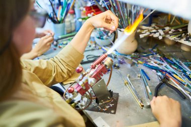 Genç kadın sanatçı glassworking Studio'da güzel el yapımı takı yaparken Gaz Meşalesi tarafından Cam eritme portresi yüksek açı