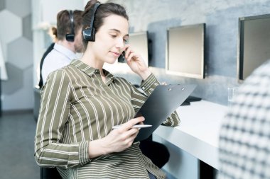 Kulaklık ve çalışma grubu sırada oturan operatörler ile holding Pano giyen genç kadın portresi